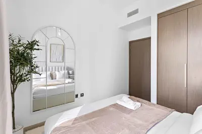 a white bedroom with a bed and a mirror at Silkhaus Heart of Downtown 3 BDR with Maid Room in Dubai