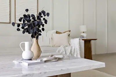 a white living room with a table and a vase with flowers at Silkhaus Heart of Downtown 3 BDR with Maid Room in Dubai
