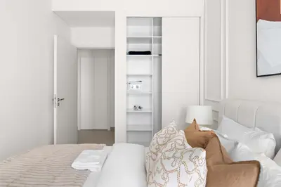 a white bedroom with a bed and a book shelf at Silkhaus Next Golf Club Golfville in Dubai Hills in Dubai