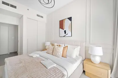 a white bedroom with a large bed and a lamp at Silkhaus Next Golf Club Golfville in Dubai Hills in Dubai