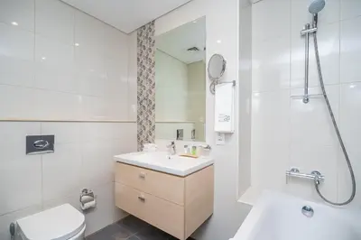 a bathroom with a sink and a toilet and a mirror at Escape24 Premium Studio in Damac Hills in Dubai