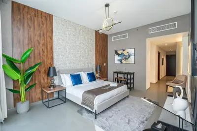 a bedroom with a bed with blue pillows at Escape24 Premium Studio in Damac Hills in Dubai