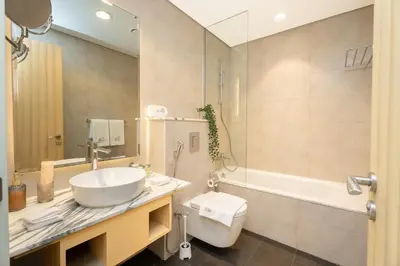 a bathroom with a sink and a tub and a toilet at Escape24 Spacious 2BR Infinity Pool with Burj Views in Dubai