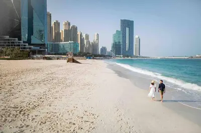 a man and a woman walking on a beach at Breathtaking 2BR with Full SeaView in Dubai