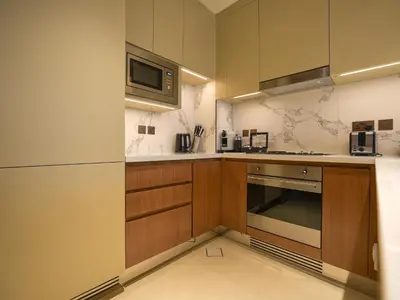 a kitchen with wooden cabinets and a microwave at Venetian - The Address Residences Dubai Opera Full Burj & Fountain Views in Dubai