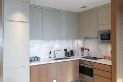 a kitchen with white marble walls and wooden cabinets at Luxury Suite at Address Residences Dubai Opera , High-Floor Ocean Views, Burj Khalifa Pool Access, Steps from Dubai Mall in Dubai