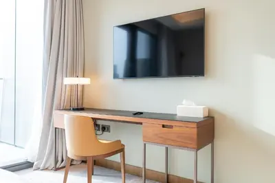 a desk with a chair and a television on a wall at Luxury Suite at Address Residences Dubai Opera , High-Floor Ocean Views, Burj Khalifa Pool Access, Steps from Dubai Mall in Dubai