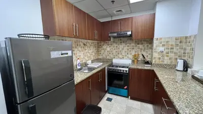 a kitchen with a stainless steel refrigerator and wooden cabinets at Venetian - Stay in Business Bay near Burj Khalifa views in Dubai