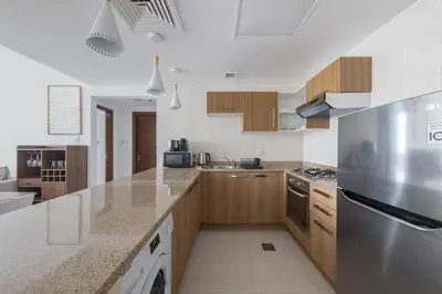 a kitchen with wooden cabinets and a stainless steel refrigerator at Stylish 2 bd Apt in Business Bay, Prime Location in Dubai