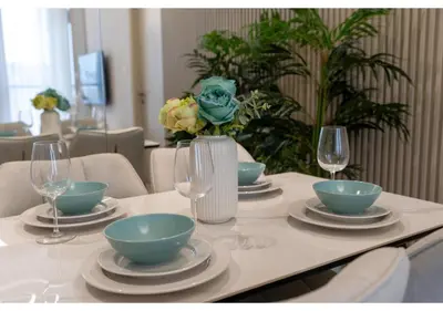 a table with bowls and plates and wine glasses at Bright and Modern 1BR Midtown Near Expo Site by Vibel in Dubai