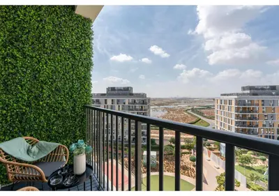a balcony with a green ivy wall and a chair at Bright and Modern 1BR Midtown Near Expo Site by Vibel in Dubai