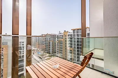 a balcony with a wooden table and a view of a city at Spacious Studio with Community and Partial Burj Khalifa Views by Deluxe Holiday Homes in Dubai