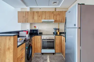 a kitchen with wooden cabinets and a stainless steel refrigerator at ShoresInn - Dreamy Marina Views in Dubai in Dubai