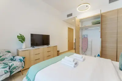 a bedroom with a bed with a television and towels at Stylish 1BR in JVC with Pool & Nearby Parks in Dubai