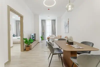 a dining room and living room with a table and chairs at Stylish 1BR in JVC with Pool & Nearby Parks in Dubai