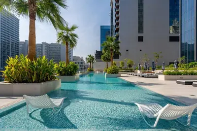 a swimming pool with two white chairs and palm trees at GuestReady - Modern retreat in Business Bay in Dubai