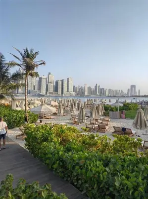 a beach with umbrellas and chairs and a city at Palm Jumeirah Seven Palm 1 Bedroom with infinity pool and Palm jumeirah beach in Dubai