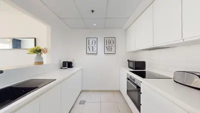 a white kitchen with white cabinets and a sink at Marina Quays - Calm One Bedroom in Dubai