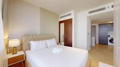 a bedroom with a large white bed with a nightstand and lamp at Sky Gardens - Cosy Studio in DIFC in Dubai