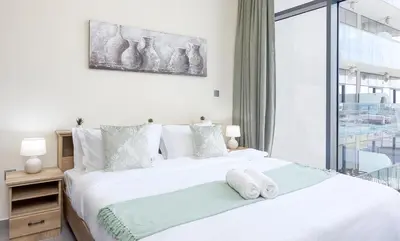 a white bedroom with two beds and a window at Chic 1BR Getaway- 4min Walk to Business Bay Metro & 10min to Burj Khalifa in Dubai