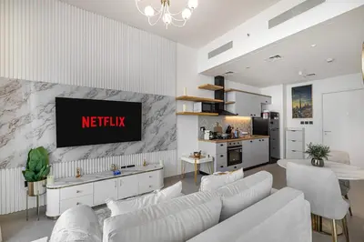 a living room with white furniture and a tv on a wall at Luxury Apt in Dubai Hills Burj Khalifa views in Dubai