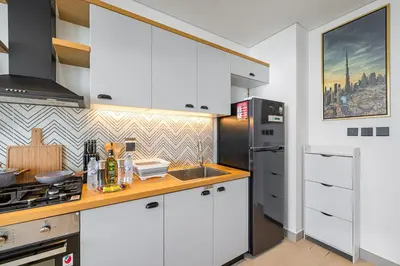a kitchen with white cabinets and a stainless steel refrigerator at Luxury Apt in Dubai Hills Burj Khalifa views in Dubai