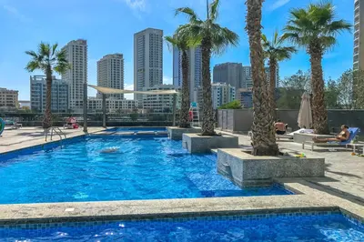 a swimming pool with palm trees in a city at Walk to JBR Beach I Marina Studio Stay I Wi-fi in Dubai
