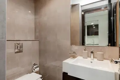 a bathroom with a sink and a mirror and a toilet at Stylish 1BR Apartment at DAMAC Merano Tower with Great View in Dubai