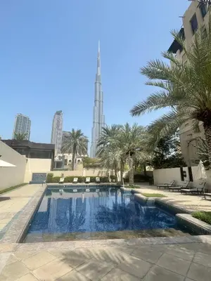 a swimming pool with palm trees and a building at Yansoon 7,Oldtown-Downtown - 2BR & Maids Room - Allsopp&Allsopp in Dubai