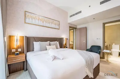 a bedroom with a large white bed and a bathroom at Inviting 2BR Apartment in Azizi Riviera 39, Al Merkadh by Deluxe Holiday Homes in Dubai