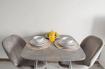 a table with two chairs and a glass of orange juice at Chic Studio Near Burj Khalifa, Dubai Opera & Dubai Mall with City Skyline Views in Dubai