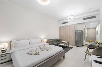 a bedroom with a large white bed and a kitchen at Chic Studio Near Burj Khalifa, Dubai Opera & Dubai Mall with City Skyline Views in Dubai