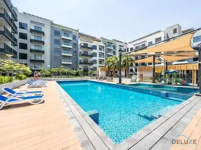 a swimming pool with lounge chairs next to a building at Captivating 1BR Apartment in Zazen Gardens, Al Furjan by Deluxe Holiday Homes in Dubai
