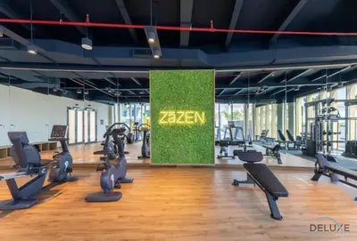 a gym with rows of treadmills and machines at Captivating 1BR Apartment in Zazen Gardens, Al Furjan by Deluxe Holiday Homes in Dubai