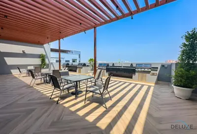 a patio with a table and chairs on a roof at Captivating 1BR Apartment in Zazen Gardens, Al Furjan by Deluxe Holiday Homes in Dubai
