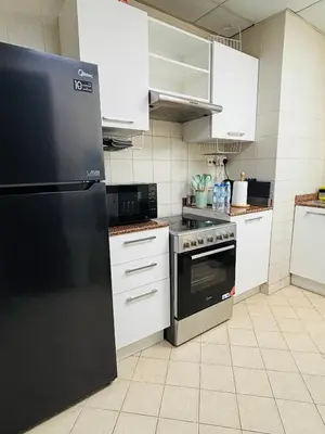 a kitchen with a black refrigerator and white cabinets at Luxury One Bedroom Apartment In Dubai Marina in Dubai