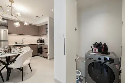 a kitchen with a washing machine and a table with chairs at Burj Crown - Urban Chic Opera Boulevard View, Walk to Dubai Mall in Dubai