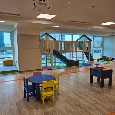 a room with a table and chairs and a playground at Spacious Studio MeDoRe Tower in Dubai