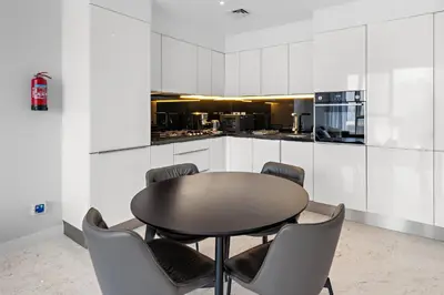 a table and chairs in a kitchen with white cabinets at InstaWorthy Aesthetic 1BR APT, 5mins to Dubai Mall in Dubai