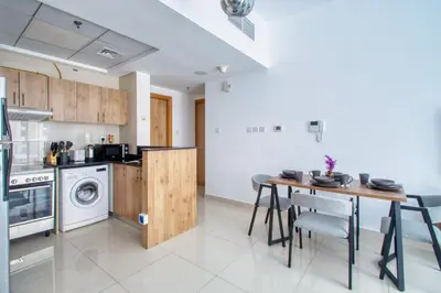a kitchen with a table and a stove and a dishwasher at ShoresInn - Cozy 1BHK in Dubai Marina in Dubai