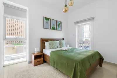 a white bedroom with a bed and two windows at ShoresInn - Cozy 1BHK in Dubai Marina in Dubai