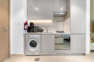 a kitchen with a washing machine and a washer at Stunning Studio w Pool & Gym in Dubai