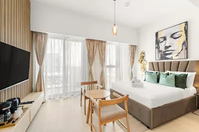 a bedroom with a bed and a table and a tv at Stunning Studio w Pool & Gym in Dubai
