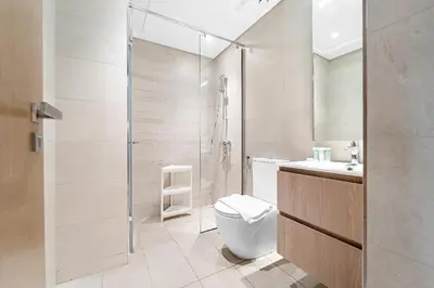 a white bathroom with a toilet and a shower at Stunning Studio w Pool & Gym in Dubai