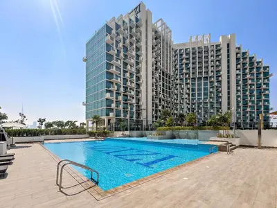 a swimming pool in front of a tall building at Stunning Studio w Pool & Gym in Dubai