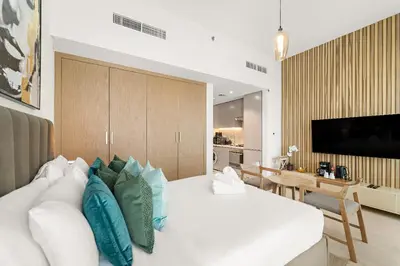 a bedroom with a white bed with blue pillows at Stunning Studio w Pool & Gym in Dubai