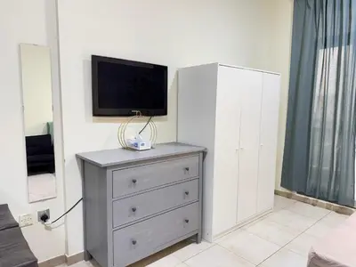 a bedroom with a dresser with a tv on it at Bright Spacious Apartment in Dubai Sports City in Dubai