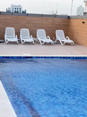 four white chairs sitting next to a swimming pool at Bright Spacious Apartment in Dubai Sports City in Dubai