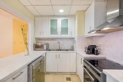 a kitchen with white cabinets and a sink at Daniels 2BR at Rimal JBR with Marina View in Dubai