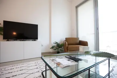 a living room with a tv and a glass table at Noma Fairview - Burj Khalifa view stunning apartment in Business Bay in Dubai